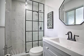 A modern bathroom with a shower, toilet, and vanity.