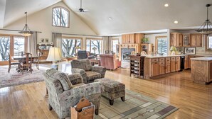 A spacious living area with a high ceiling, wooden flooring, and a large window overlooking a snowy landscape. - Pet-friendly Family Home Situated on Green Lake! (Green Lake)