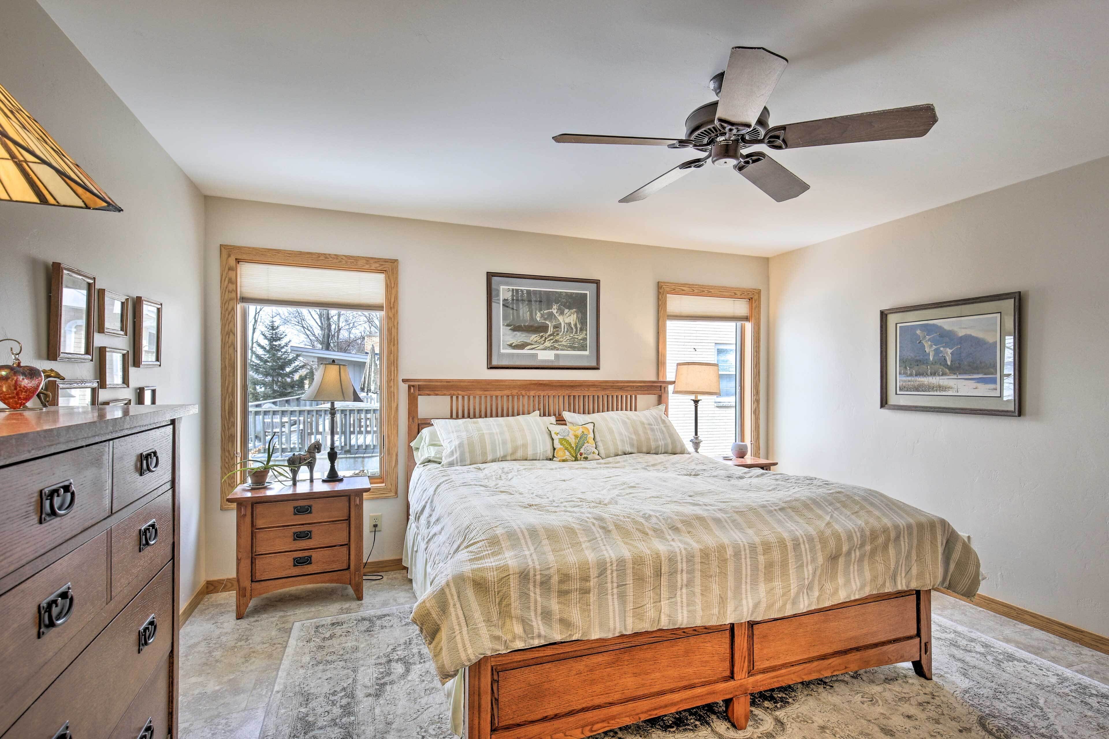 A bedroom with a wooden bed, a nightstand, a dresser, and a ceiling fan.