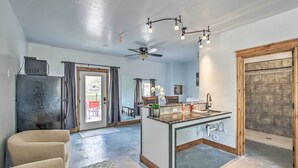 Een moderne keuken met een centraal kookeiland, een plafondventilator en een stenen open haard.