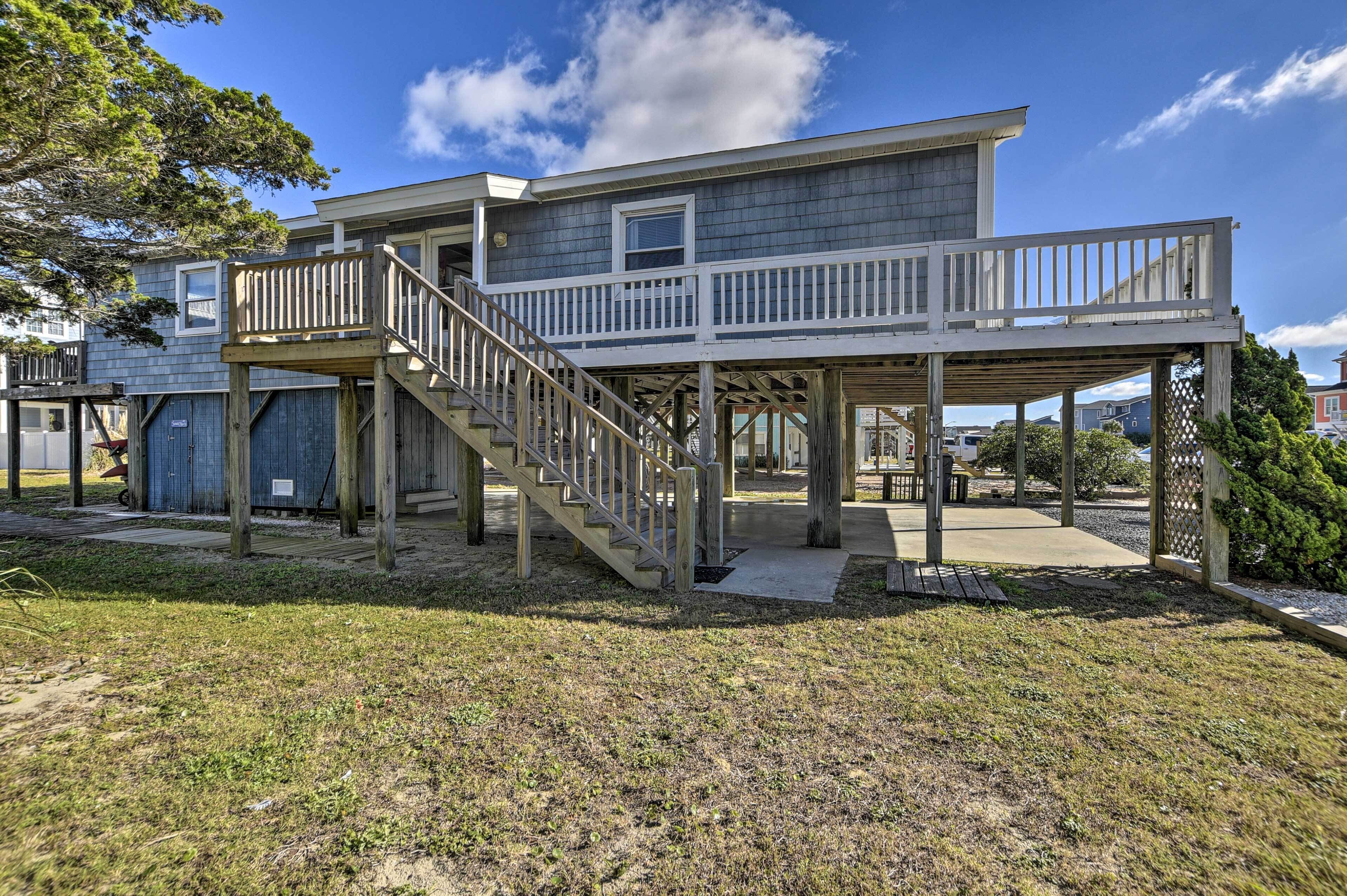 A two-story house with a wooden deck and a staircase leading to a balcony.