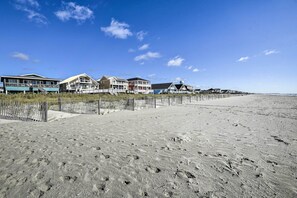 A beachfront property with multiple houses, a sandy beach, and a clear blue sky.