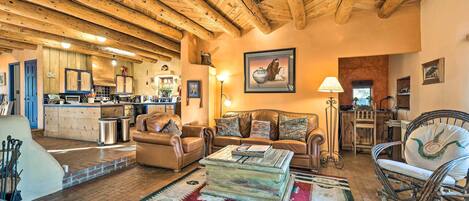 Una sala de estar acogedora con chimenea, sofás de cuero y techo de madera.