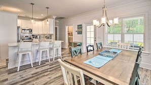 Una cocina amplia con armarios blancos, una mesa de comedor de madera y taburetes de bar.