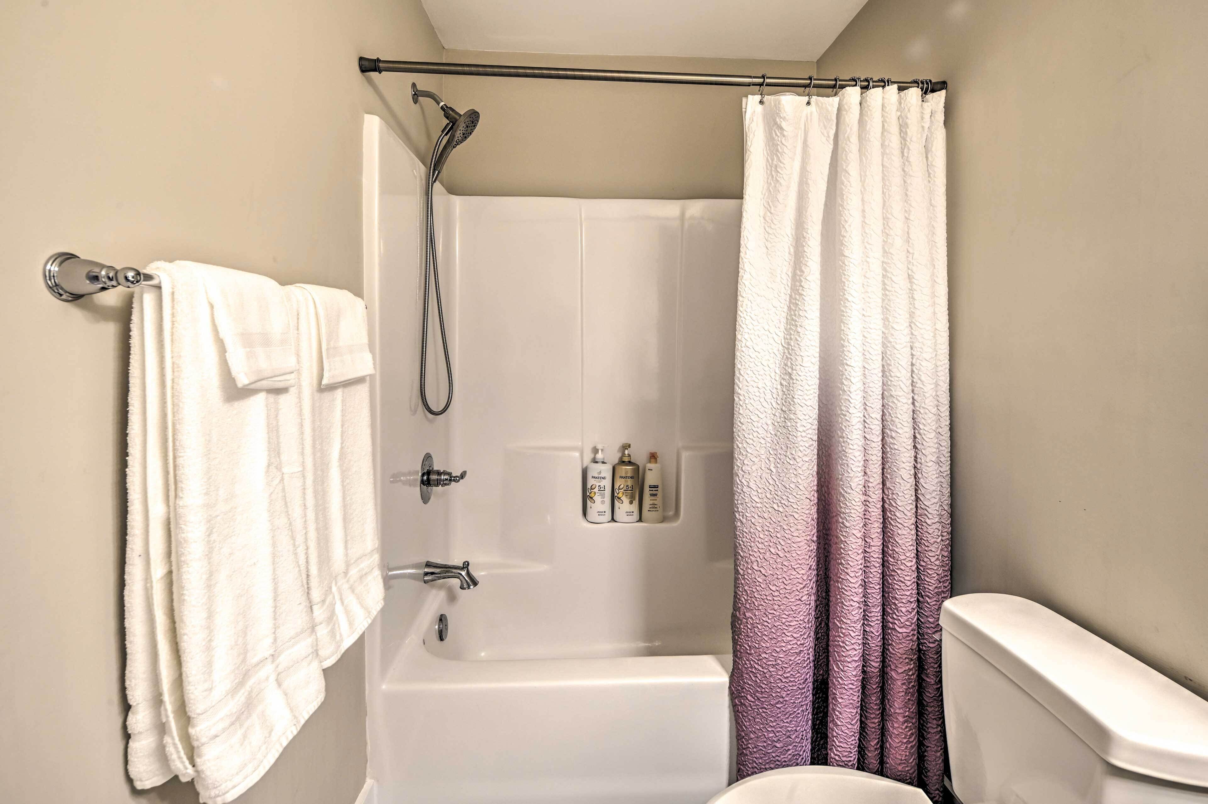 A bathroom with a bathtub, a shower, a toilet, and a towel rack with towels.
