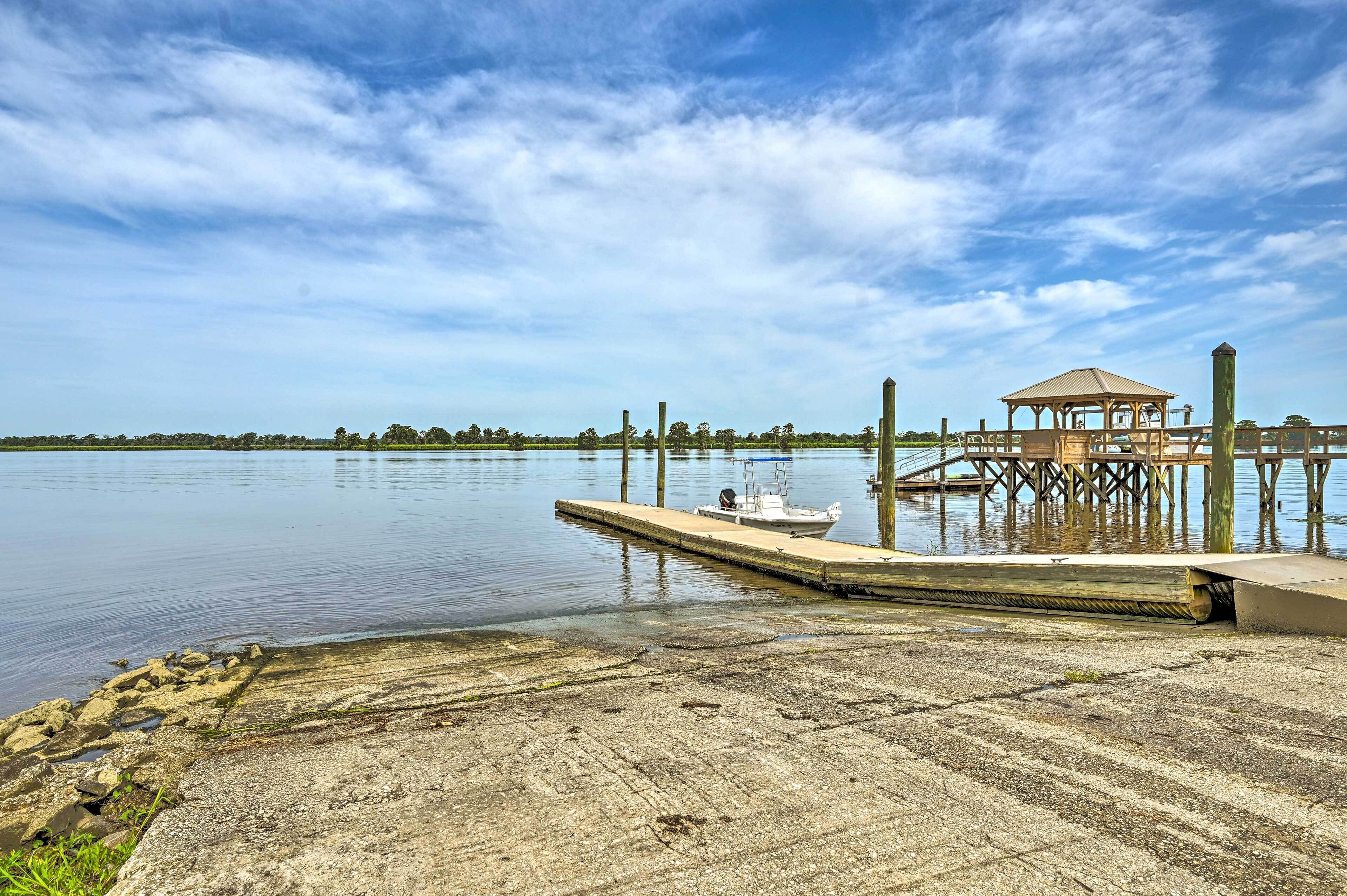 A dock extending into calm water with a gazebo and a small boat moored at the end.