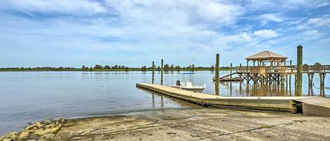 A dock extending into calm water with a gazebo and a small boat moored at the end.