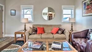 A living room with a beige sofa, two red pillows, a glass coffee table, and a brown leather armchair. - Downtown Lafayette, Colorado, Vacation Rental! (Lafayette)