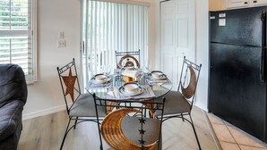 A dining area with a glass table set for four, surrounded by wicker chairs with star designs. - Sunny Port St Lucie Condo: Golf, Swim & Unwind! (Port Saint Lucie)