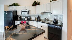 A modern kitchen with white cabinets, a black refrigerator, a microwave, a toaster, and a dishwasher. - Sunny Port St Lucie Condo: Golf, Swim & Unwind! (Port Saint Lucie)