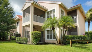 A two-story building with balconies, a covered patio, and a well-maintained lawn. - Sunny Port St Lucie Condo: Golf, Swim & Unwind! (Port Saint Lucie)