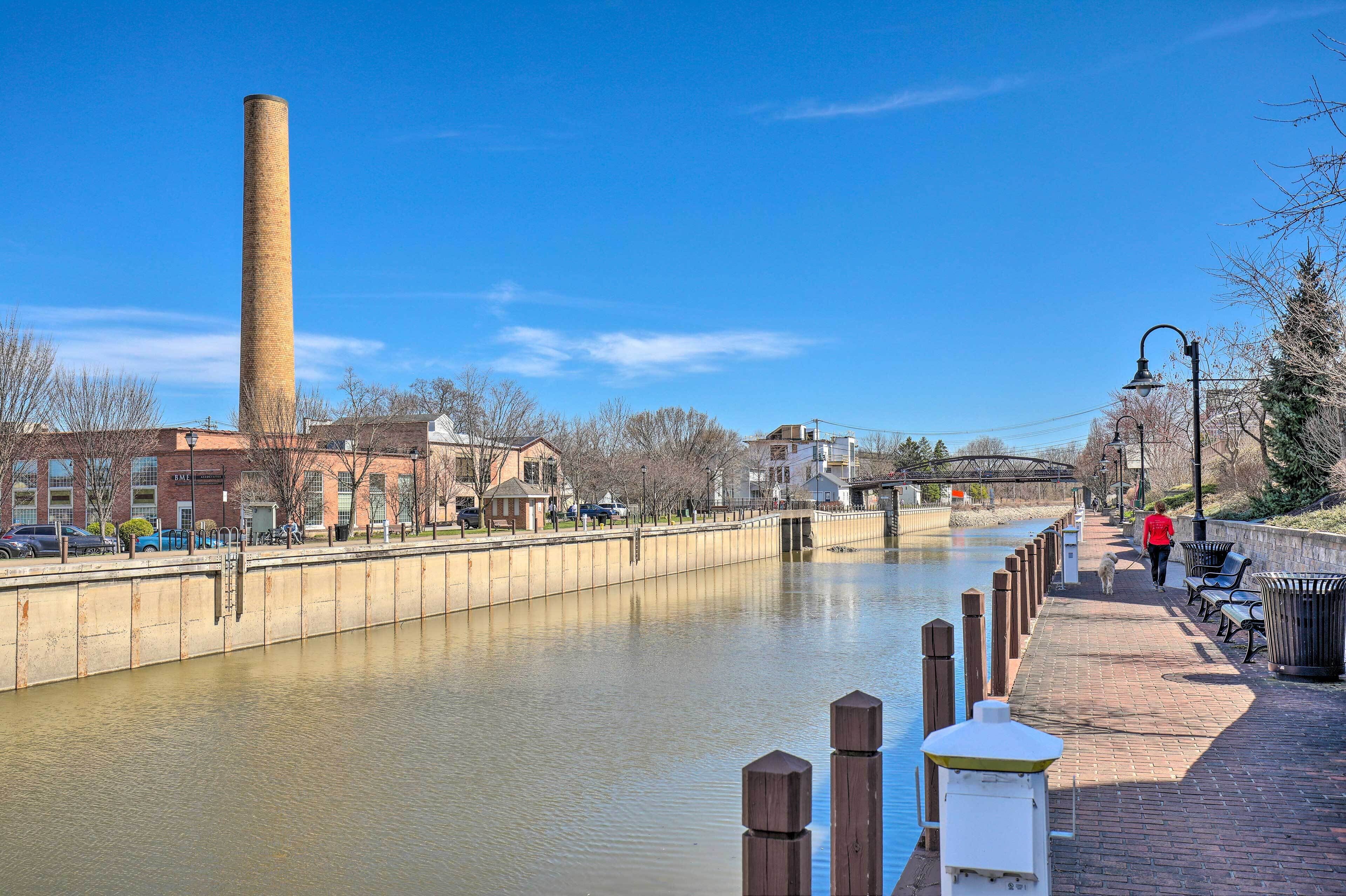 A canal with a brick building and a tall chimney in the background.