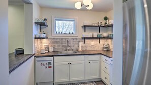 Una cocina moderna con armarios blancos, un refrigerador de acero inoxidable, un ventanal con vistas y una cubierta de azulejos azules.