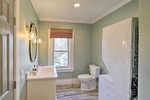 Bathroom features a toilet, sink, and mirror, with a washing machine and wooden floor.