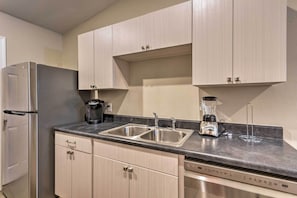 A modern kitchen with stainless steel appliances, a double sink, and light-colored cabinetry.
