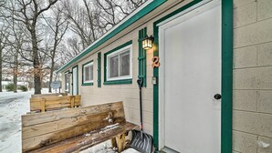A snow-covered bench outside a building with a door marked with the number 2.