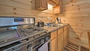 A kitchen with wooden walls, a stainless steel stove, a toaster, and a sink.