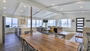 Una cocina amplia con una gran mesa de madera, electrodomésticos modernos y vista al océano.
