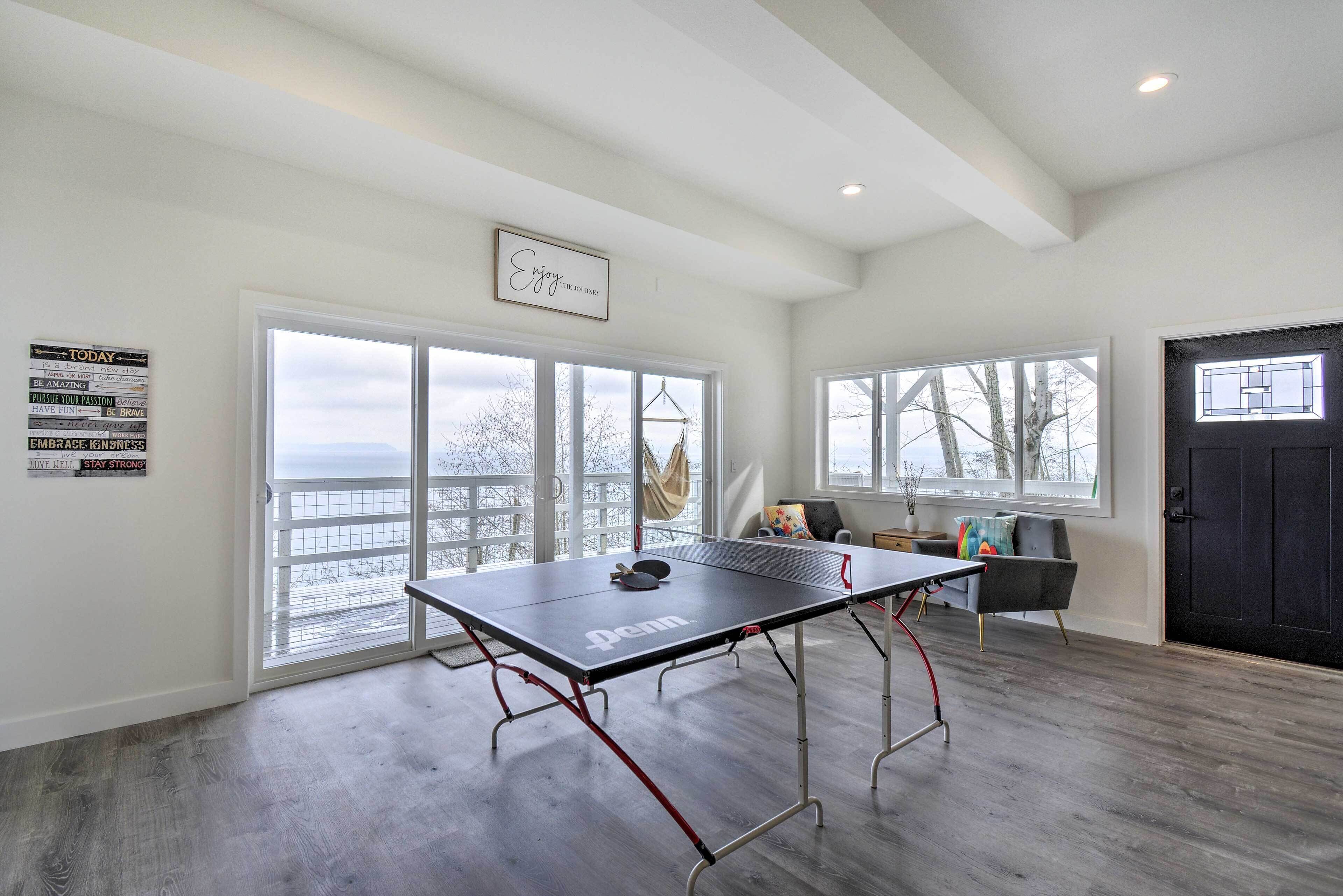 Una habitación amplia con mesa de ping pong, ventanas grandes con vistas e imágenes motivacionales en las paredes.