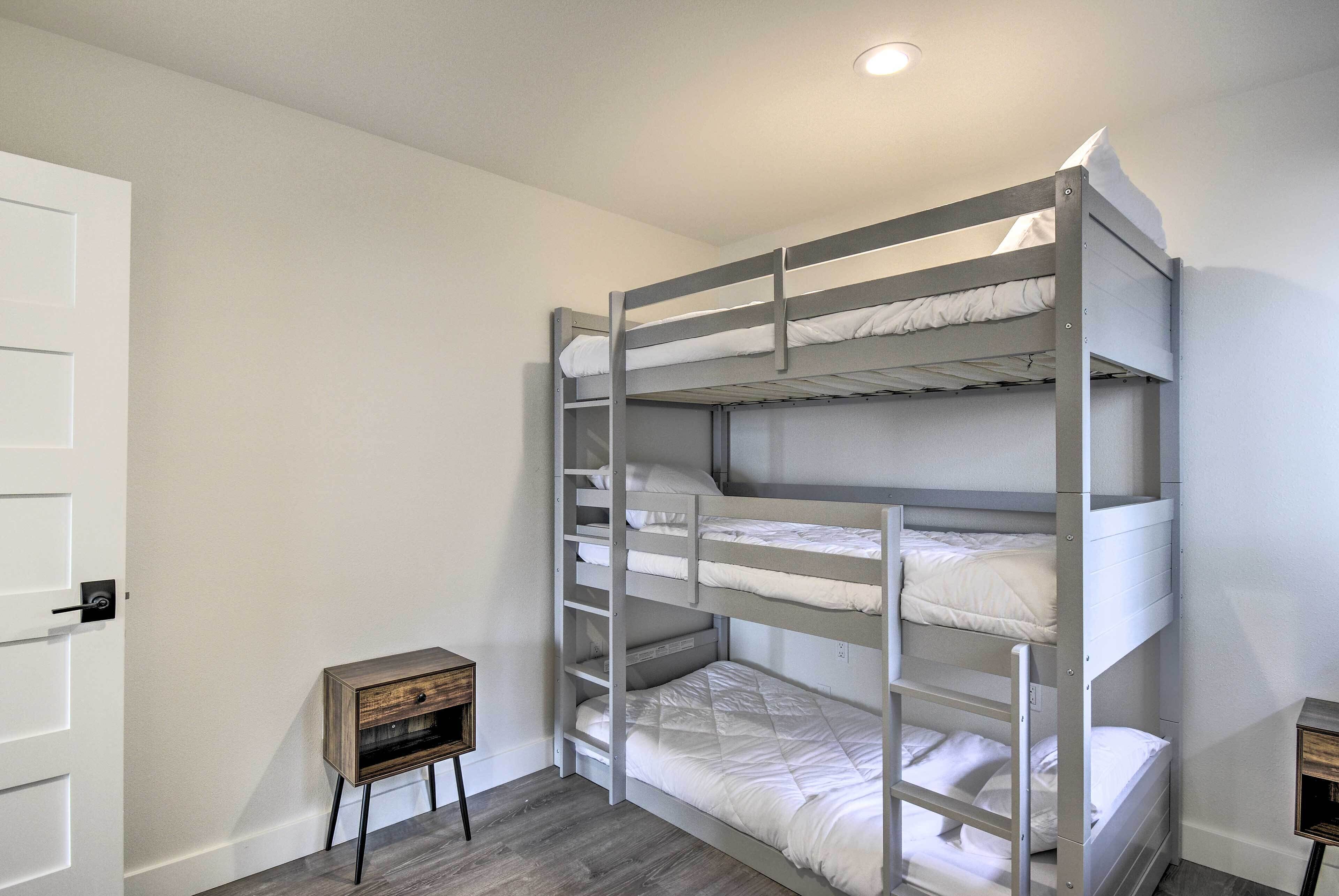 A bunk bed room with a small wooden nightstand and a white door.
