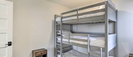 A bunk bed room with a small wooden nightstand and a white door.