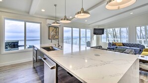 Una cocina amplia con una isla grande, iluminación colgante y vistas al océano.