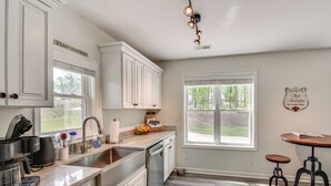 A kitchen with white cabinets, a coffee maker, a sink, and a window with a view of the outdoors. - Waterfront Townville Home: Hot Tub & Lake Access! (Townville)