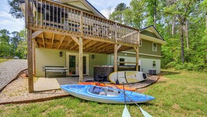A two-story wooden house with a covered porch, a kayak, and paddles on the grass. - Waterfront Townville Home: Hot Tub & Lake Access! (Townville)
