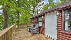 A log cabin with a wooden deck, two Adirondack chairs, and a white garage door. - Cassopolis 'the Cabin' Retreat: Lake Access! (Cassopolis)