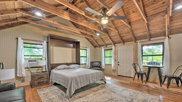 A spacious bedroom with a large bed, a desk, and two chairs. - Cassopolis 'the Cabin' Retreat: Lake Access! (Cassopolis)