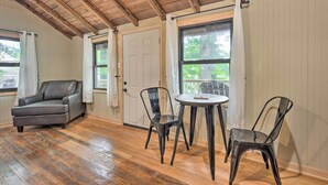 A room with a wooden floor, a leather chair, a dining table with two chairs, and a door with a window. - Cassopolis 'the Cabin' Retreat: Lake Access! (Cassopolis)