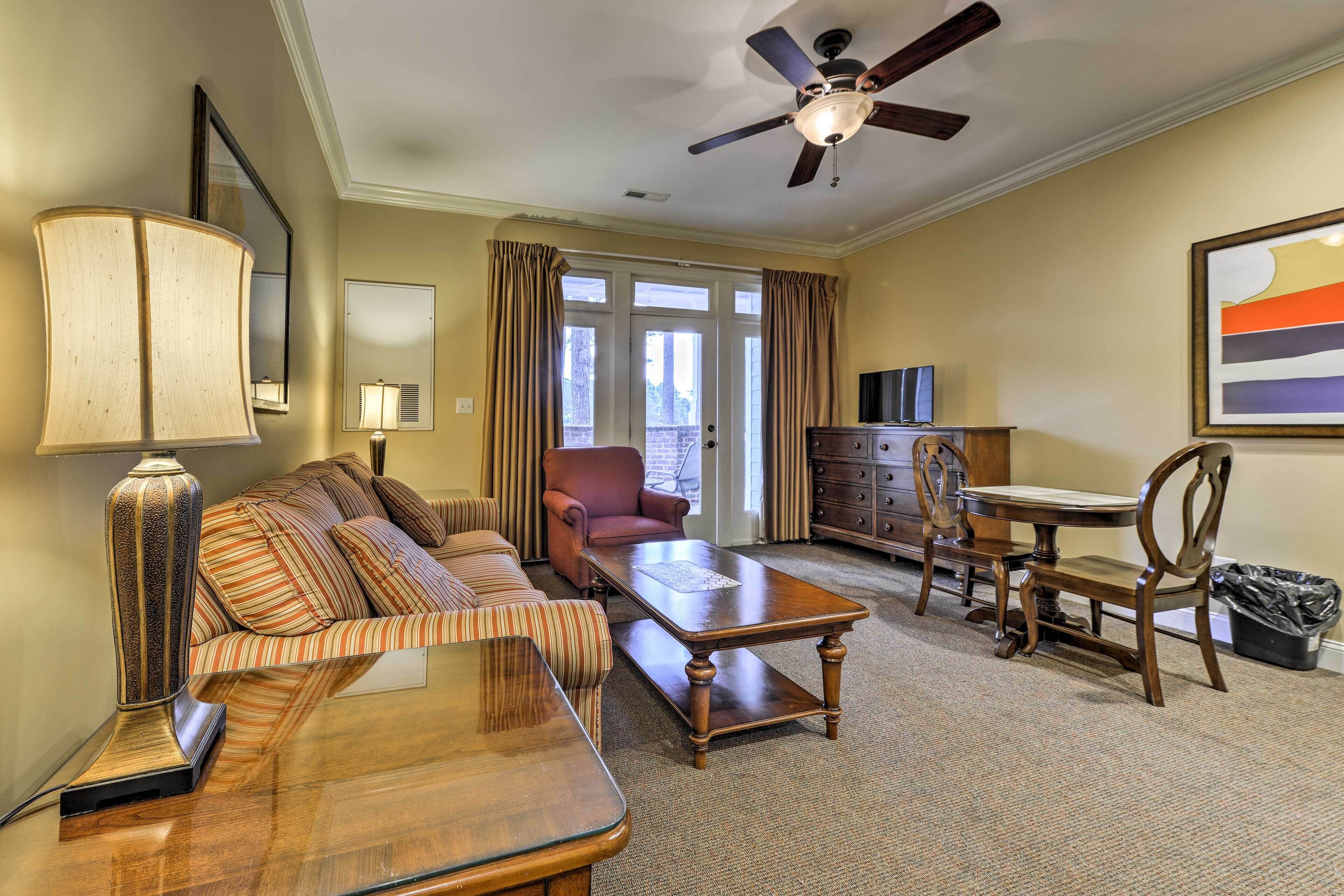 A well-lit living room with a sofa, armchair, coffee table, and a ceiling fan.