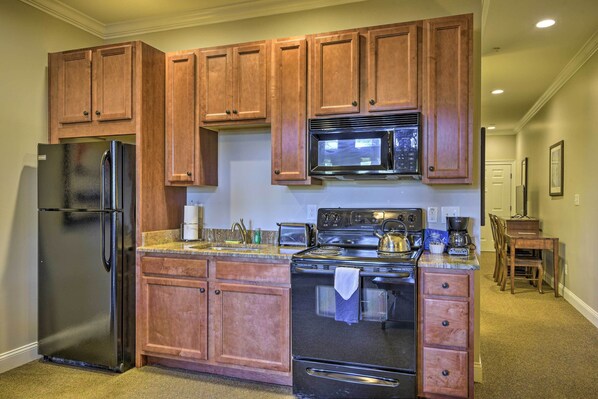 A kitchen with wooden cabinets, a stainless steel refrigerator, a microwave, and a stove. - Resort-style Condo on Golf Course w/ Pool Access (Spring Lake)