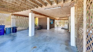 Eine offene Garage mit Betonboden, Holzbalken und einem Fahrrad.