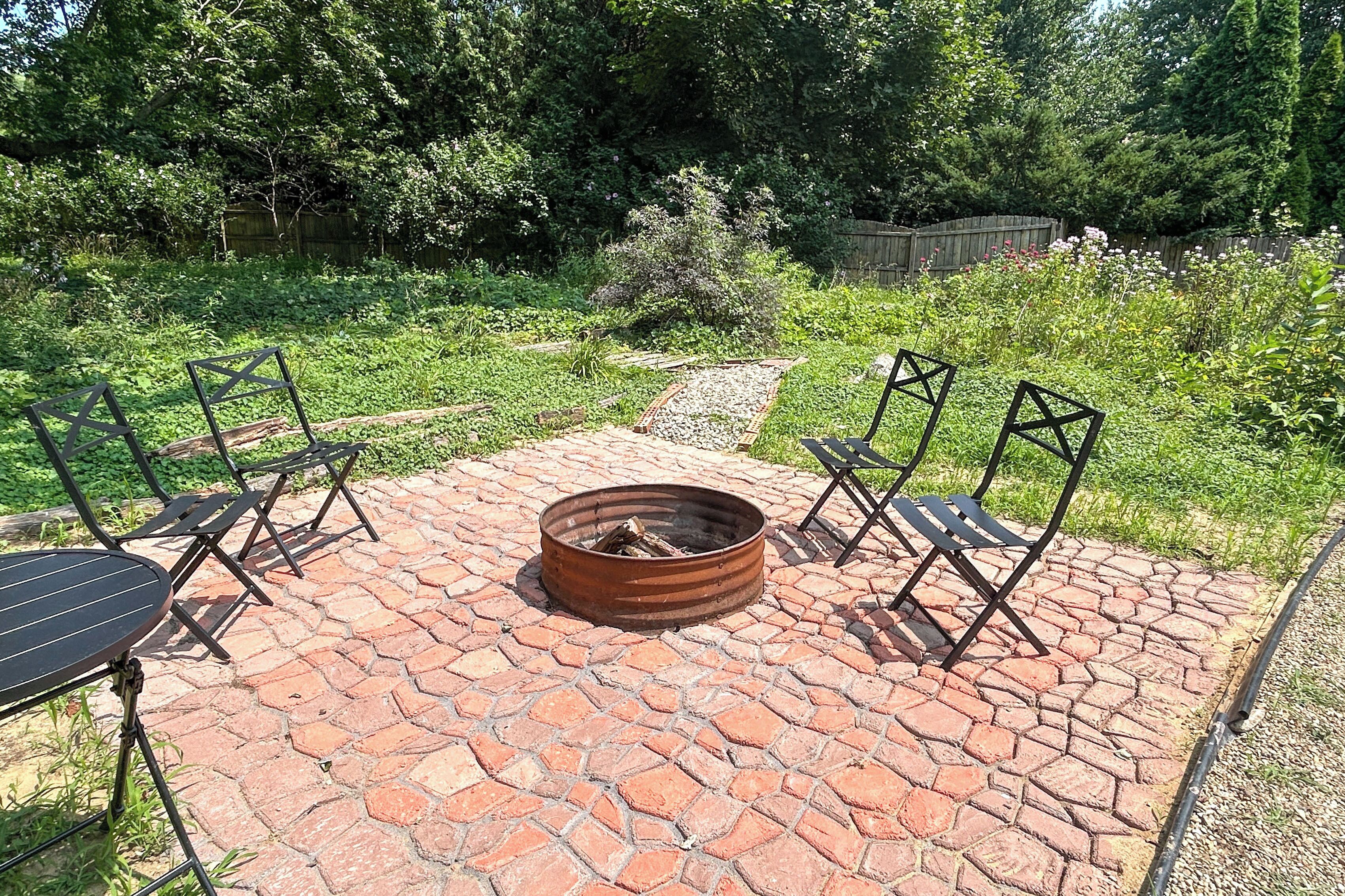 An outdoor patio with a fire pit, seating, and a garden view.