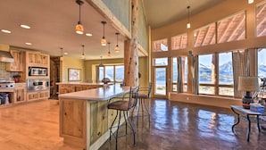 A spacious kitchen with wooden cabinets, a large island with bar stools, and large windows offering mountain views.