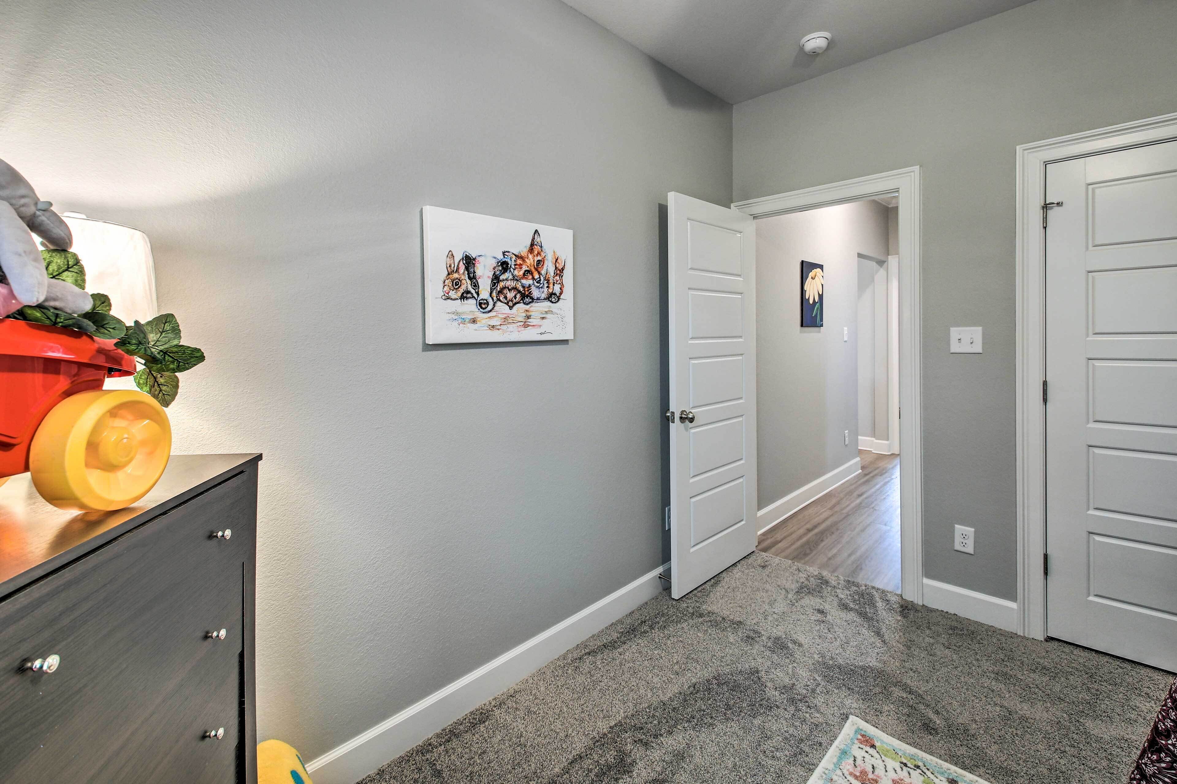 A hallway with a grey carpet, a painting of foxes, and a door leading to another room.