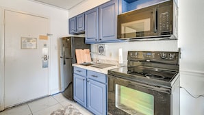 A compact kitchen with blue cabinets, a stainless steel refrigerator, a microwave, and a stove. - 4 Mi to Broadway at the Beach: Oceanfront Getaway (Myrtle Beach)