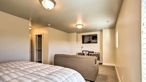A bedroom with a bed, a sofa, a television, and a door leading to a bathroom. - St George Area Townhome w/ Patio + Pool Access (Washington)