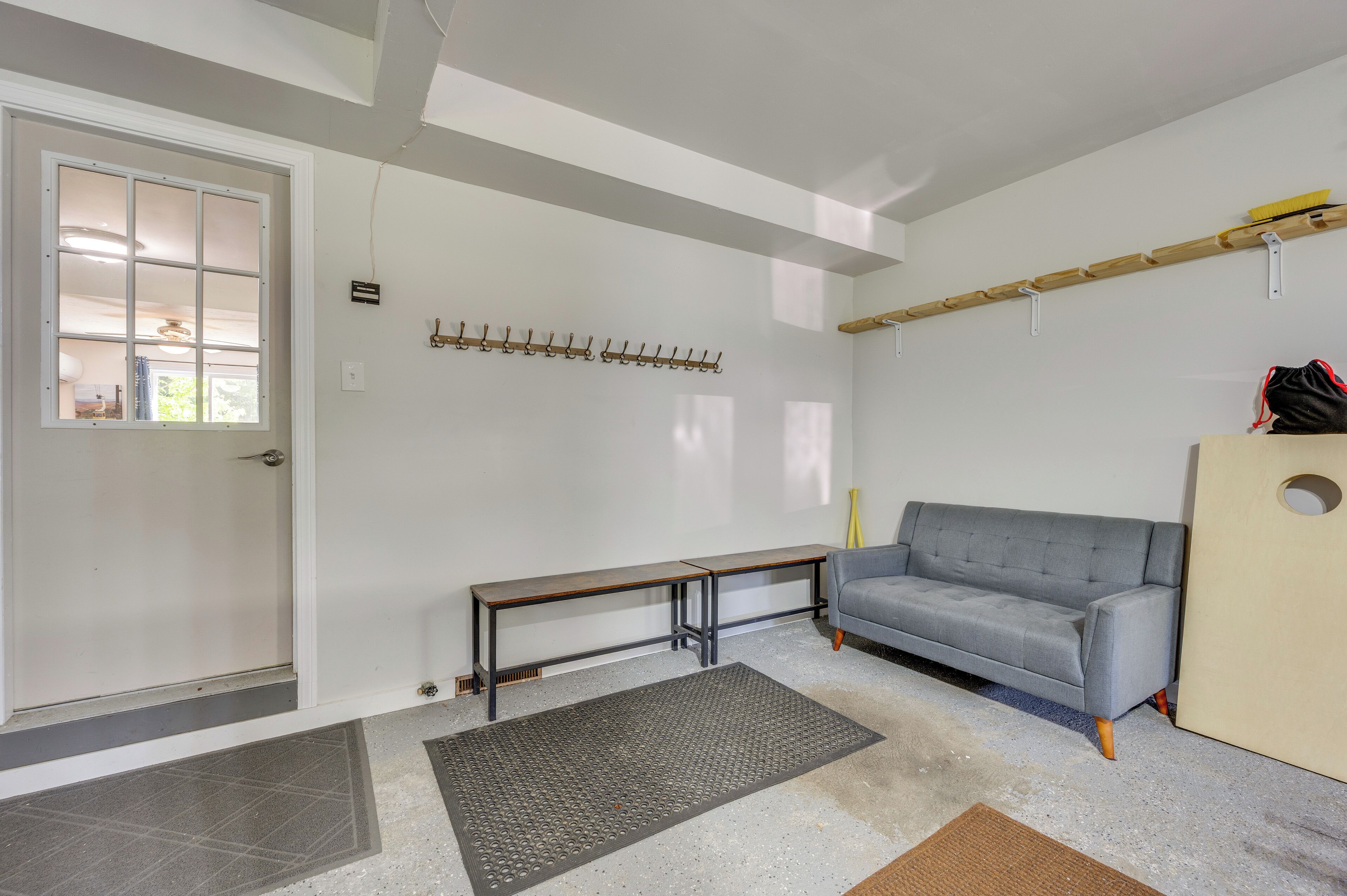 Ein modernes Wohnzimmer mit einem grauen Sofa, einer Bank und einem Kleiderständer.