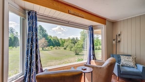 A room with a large window, two chairs, a small table, and a blue armchair. - Peaceful & Private Franconia Home by Cannon! (Franconia)