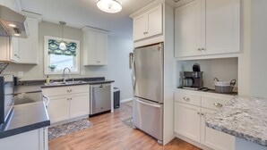 A modern kitchen with white cabinetry, stainless steel appliances, and a granite countertop. - Sunny Cloquet Home - 2 Mi to St. Louis River! (Cloquet)
