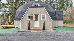 Une maison de plain-pied avec un toit à pignon, une porte d’entrée et deux fenêtres.