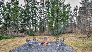 Un foyer entouré de quatre chaises, situé dans un cadre naturel avec des arbres en arrière-plan.