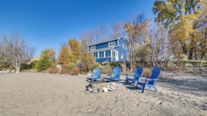 A beach house with a fire pit and blue Adirondack chairs. - Alburgh Lake House: Private Beachfront! (Alburg)