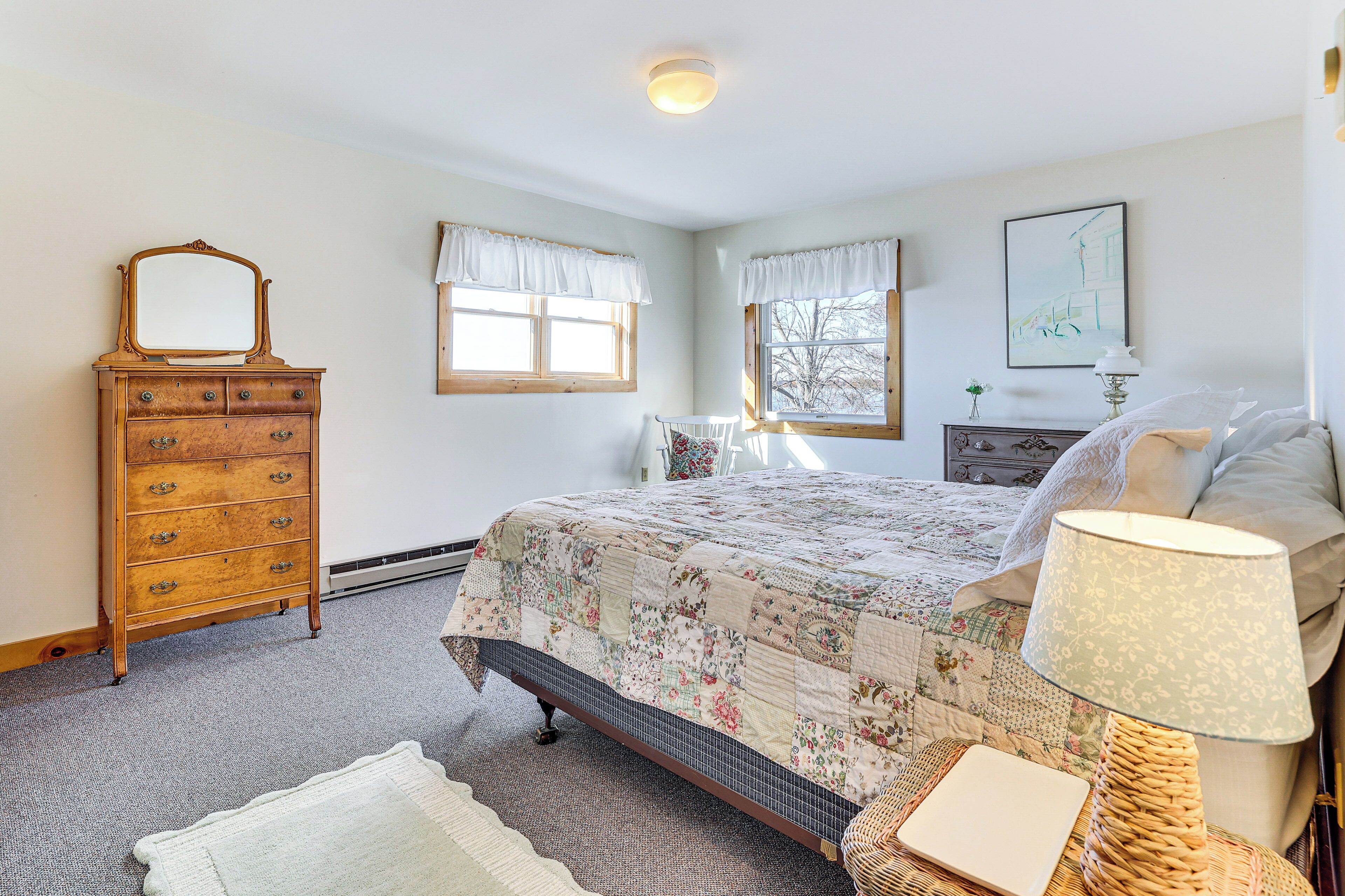 Un dormitorio con cama, cómoda y ventanas.