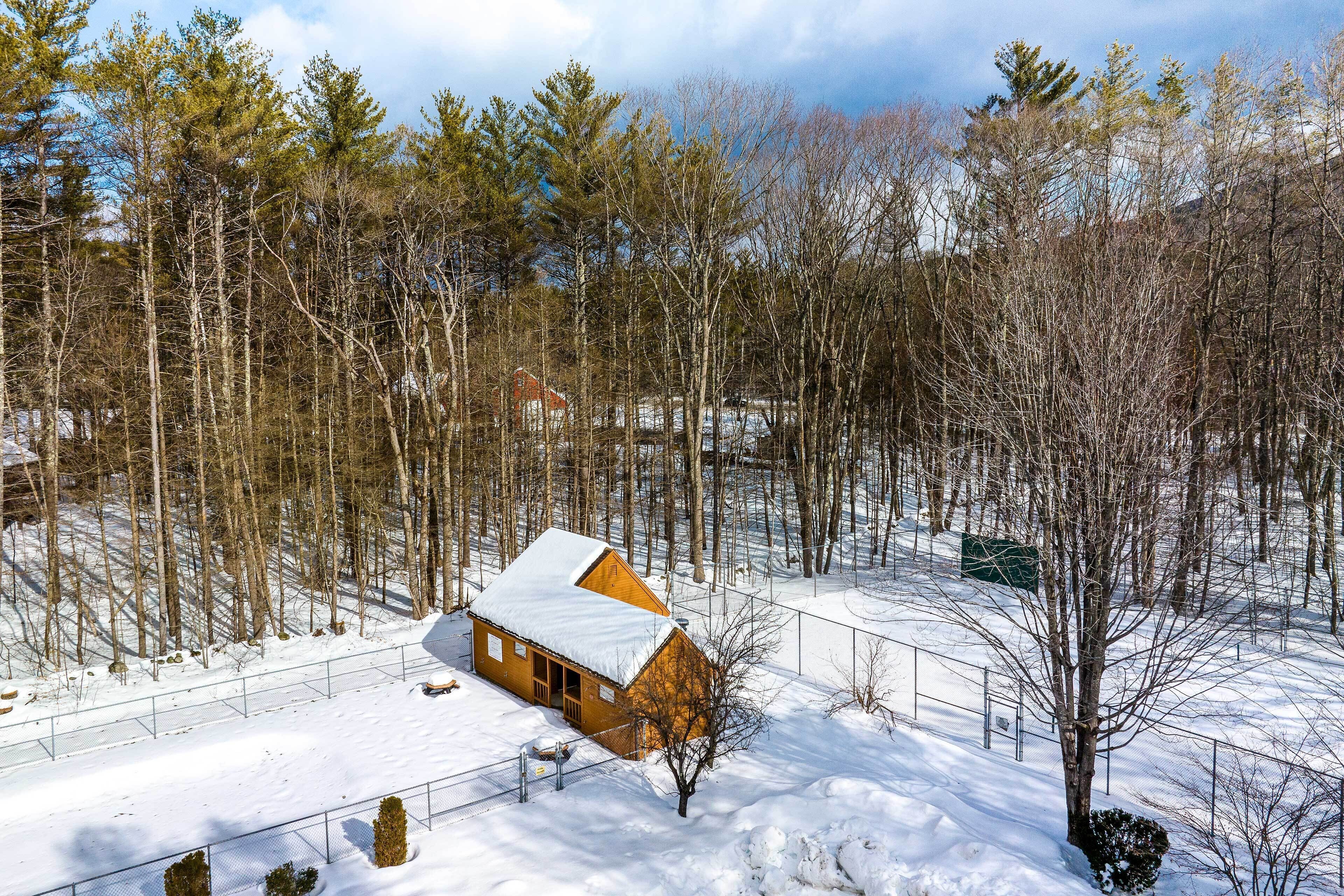 A wooden cabin surrounded by a snowy landscape with tall trees.