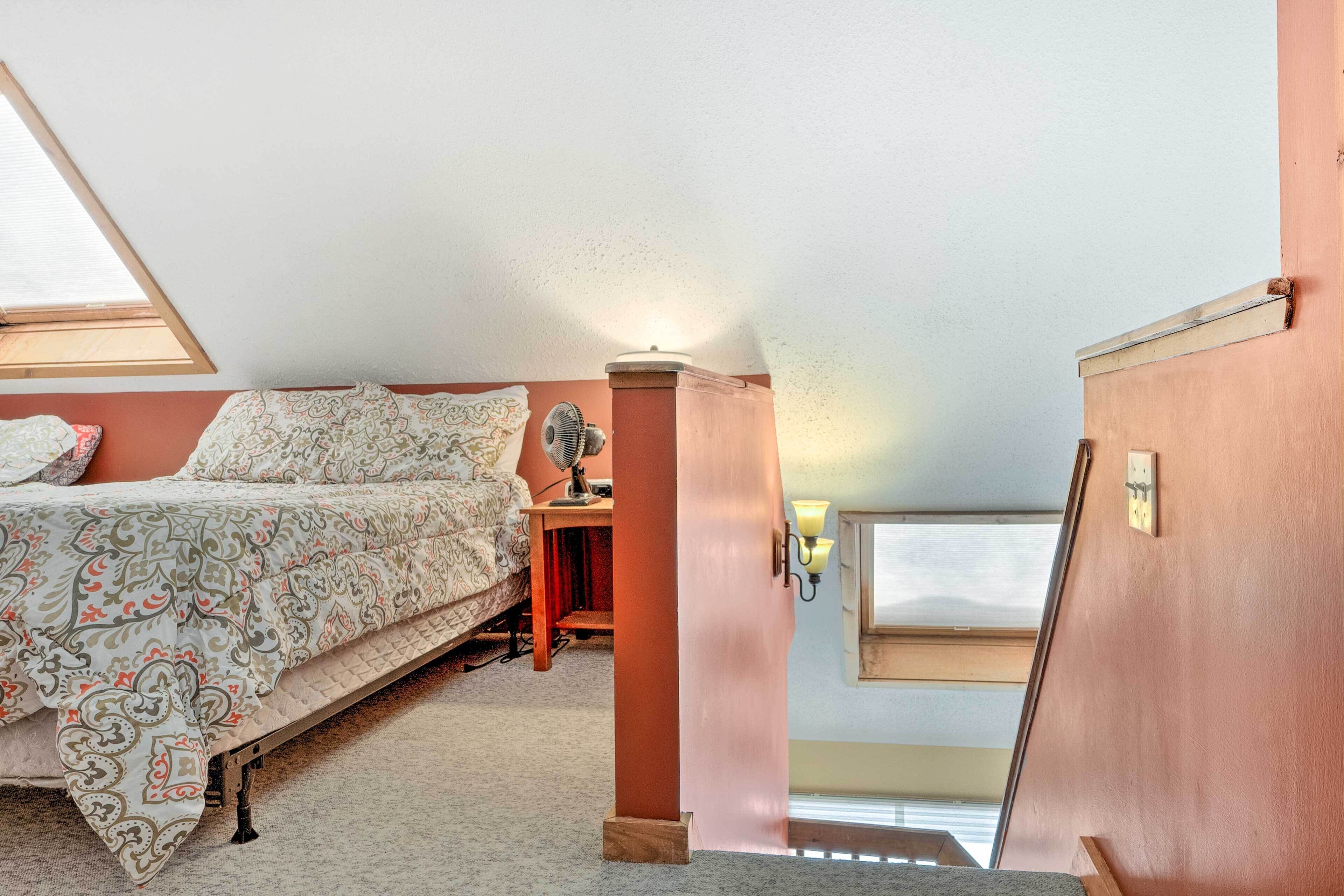 Een slaapkamer met een bed, bureau, lamp en raam.