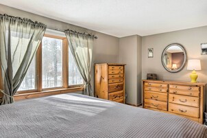 Un dormitorio con cama, cómoda de madera y ventana con cortinas.