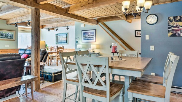 A dining area with a wooden table and chairs, a chandelier, and a clock on the wall. - Cozy Conway Area Home ~ 4 Mi to Cranmore Mountain! (Intervale)